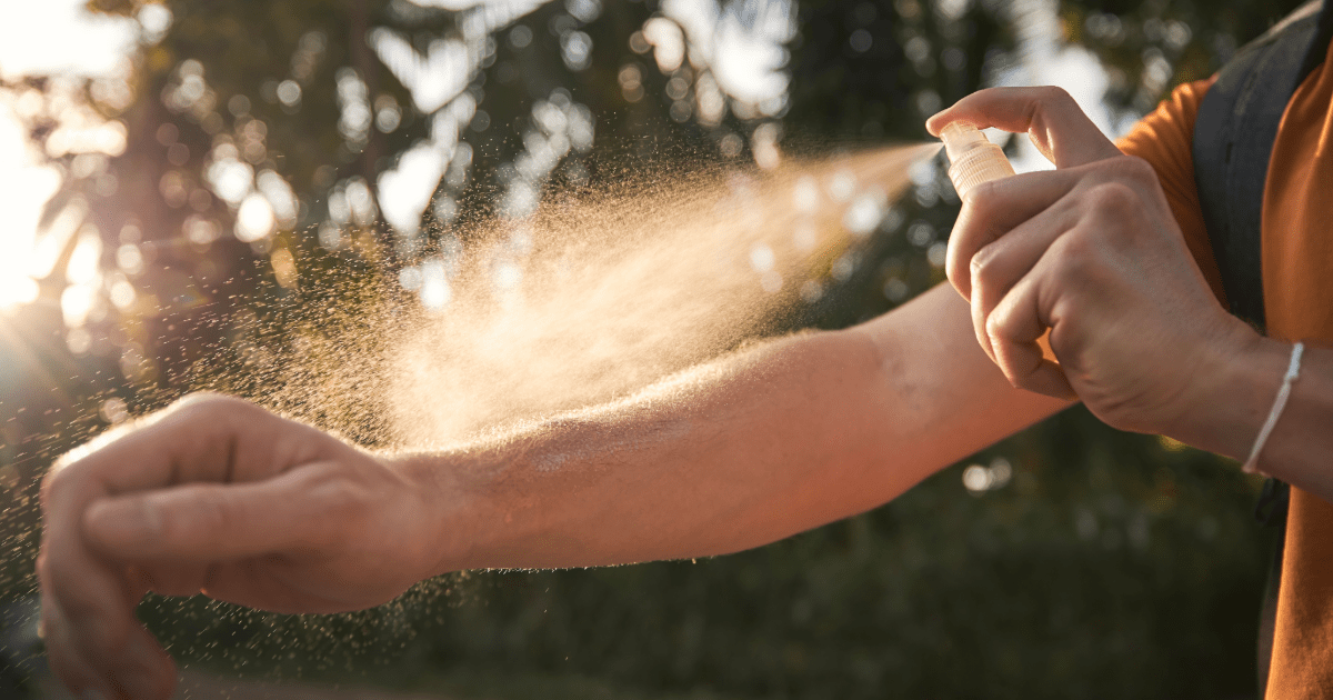 A woman spraying bug spray on her arm for effective mosquito management.